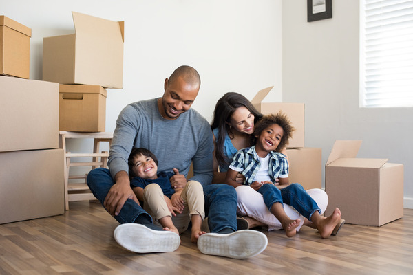 Family with two children laughing sitting near moving boxes