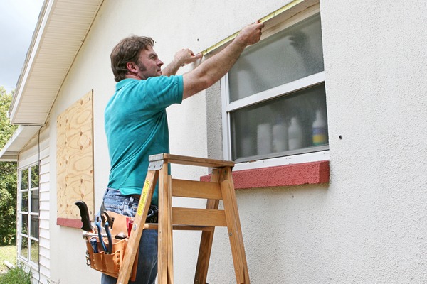 man measuring exterior of window