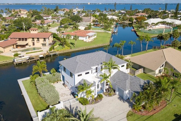 Aerial view of large homes near a canal with palm trees