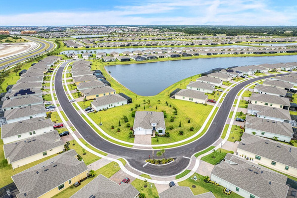 aerial view of homes surrounding a pond with a road