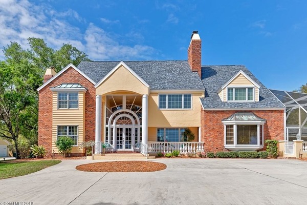 front view of a large home with red bricks, tan siding