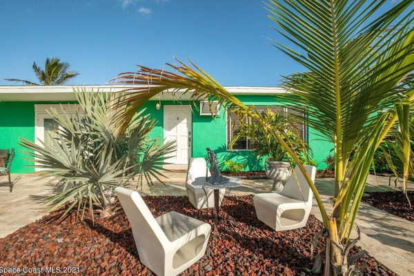 palm trees and outdoor furniture in front of green quad-plex