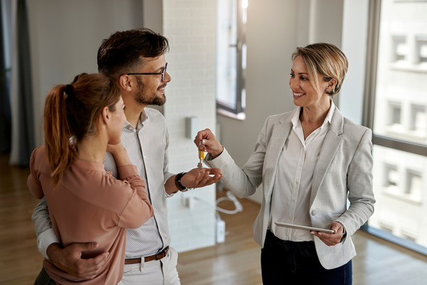 woman handing house keys to young couple