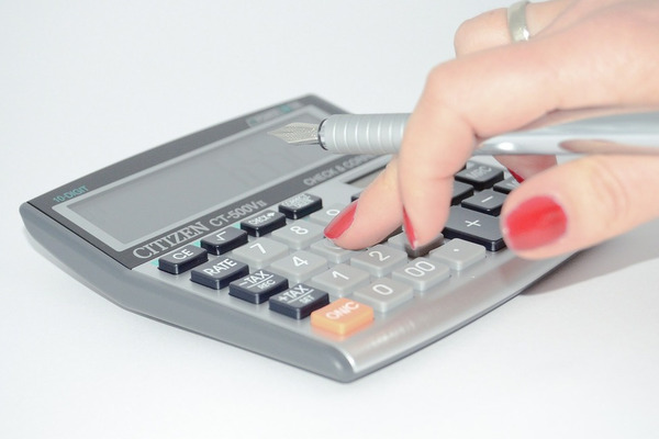 close-up of woman's hand using calculator holding pen
