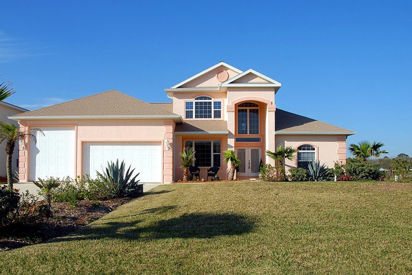 Peach home with brown roof and tall arch at front door