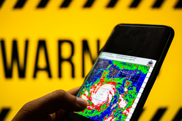 phone with hurricane on radar and yellow warning sign 