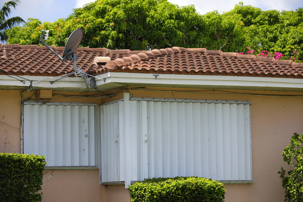 hurricane shutters on a tan house with tile roof