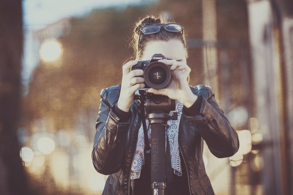 woman aiming Canon camera on tripod at user