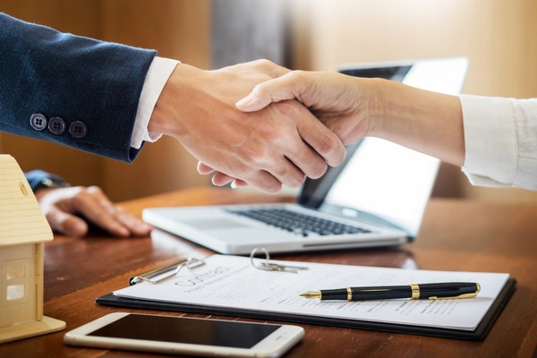 close up of man and woman shaking hands over property deal