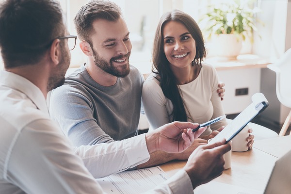 couple with realtor reviewing paperwork for sale of home