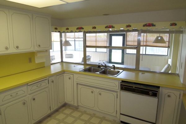 Kitchen prior to remodel with yellow Formica counters, drop ceiling lights, dated cabinetry and appliances