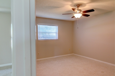 Final image of bedroom #2 where a new ceiling fan and simple vertical blinds are in keeping with a clean palate 