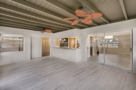 After- Ceiling color lightened, but still contrasting to beige wall color, vinyl plank flooring replaces carpet.  Pass through bar to kitchen lengthened to provide additional seating