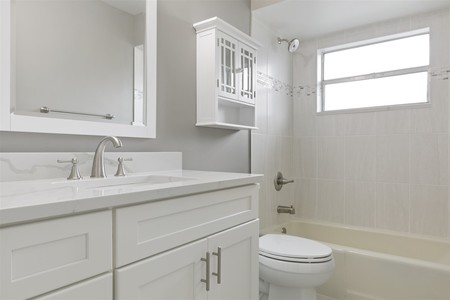 After - Only the tub remains!  White shaker vanity and quartz countertop along with new tile and framed mirror refresh the space