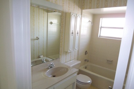 Before - Second bath sported 70s era flooring, wallpaper, vanity and fixtures