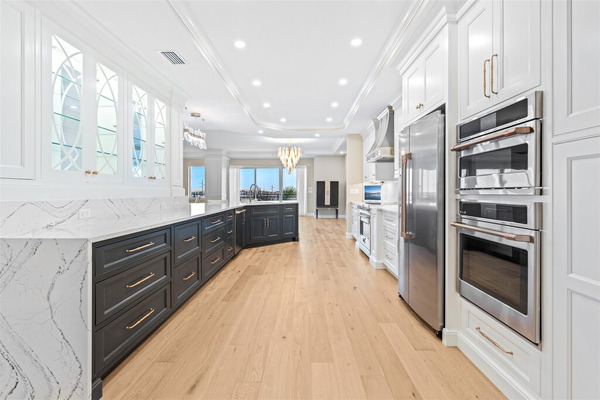 Waterfall counters, dark lower and white upper cabinetry with mixed metal fixtures