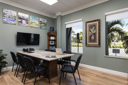 Conference Room 1 is adorned with crown molding and a custom made table with monitor for agent and client meetings.