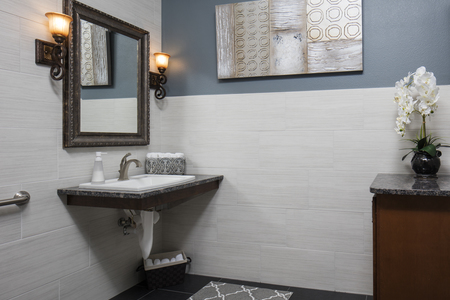 One of three bathrooms in the building. Stylish large tile walls and floor, custom ADA sink, sconces, mirror and storage cabinet.                                              