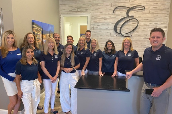 Agents, office staff and Greg Ellingson in office lobby wearing navy E shirts and light pants 