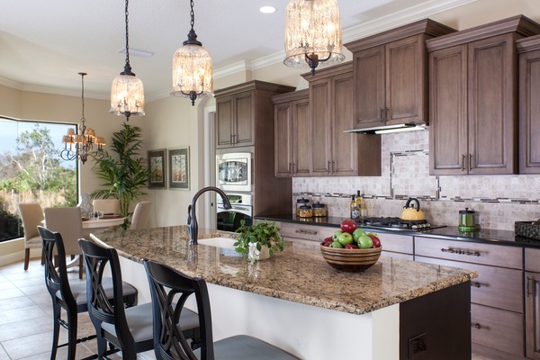 Island provides seating as well as divides great room from kitchen area.  triple pendant lights illuminate the island with staggered cabinets along wall