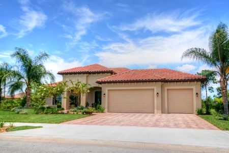 Front elevation of home features front entry 3 car garage, covered entry and paver driveway