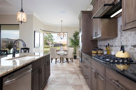 Stunning chocolate staggered cabinetry with crown molding adorns the kitchen