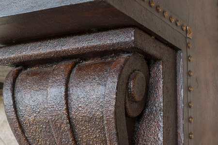 Close up of fume hood corbel showing rich brown faux finish with golden tack detail