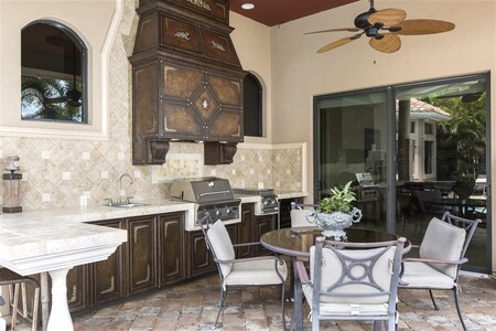 Summer kitchen built under existing lanai features grill, hood, fridge and huge L shaped counter for seating and food prep 